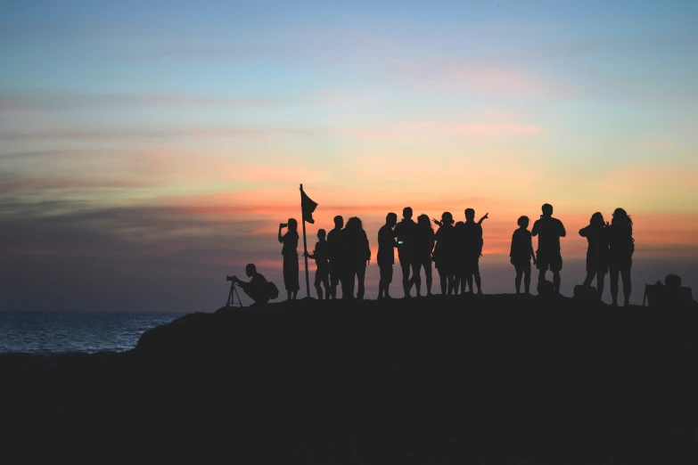 a group of people standing on top of a mountain next to the ocean