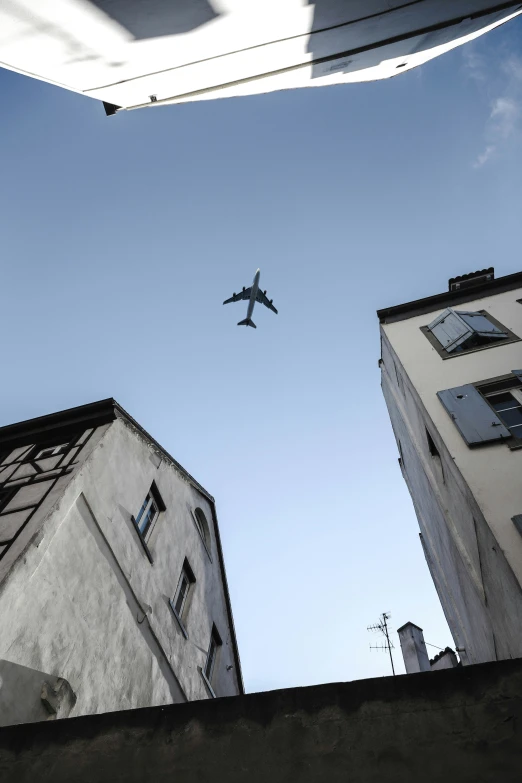 a plane flies through the air between two buildings