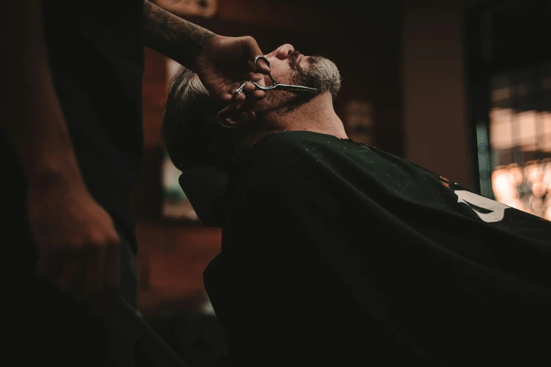 man getting his hair cut with scissors at his head