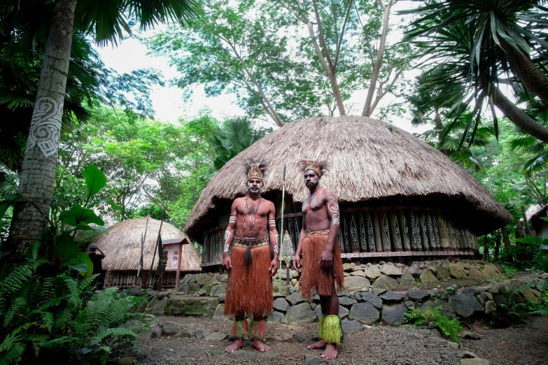 the men are standing by a small building in the woods