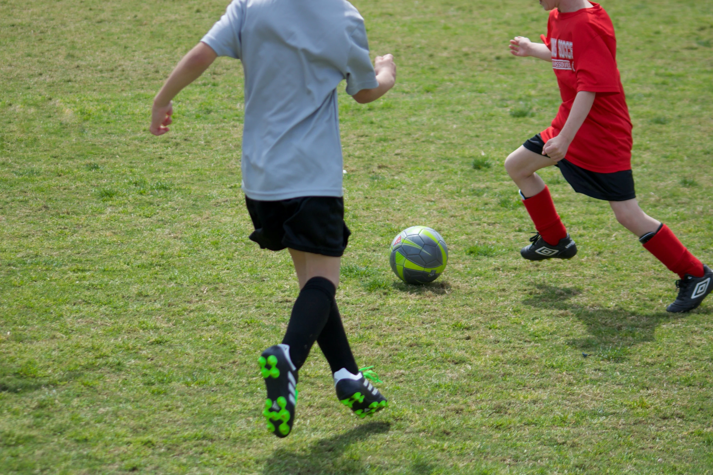 two boys playing soccer against each other in a field