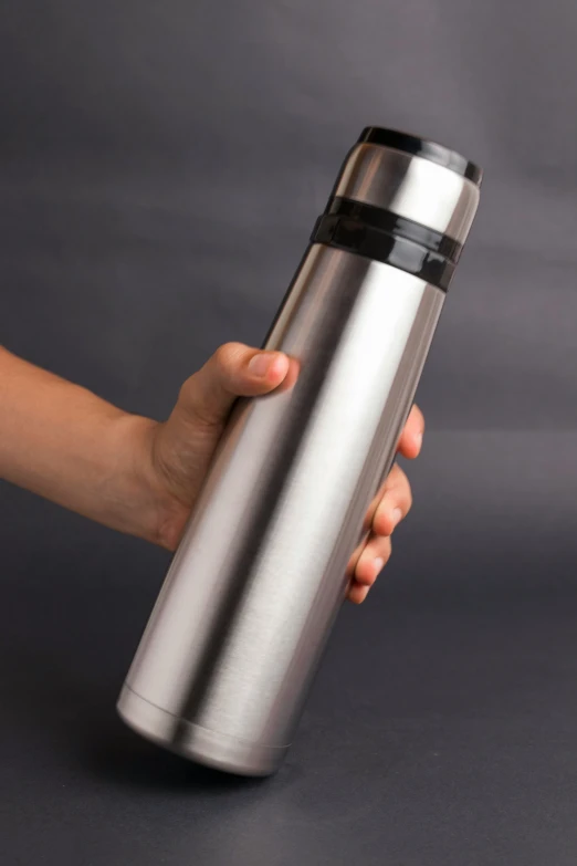 a hand holding a stainless steel thermos