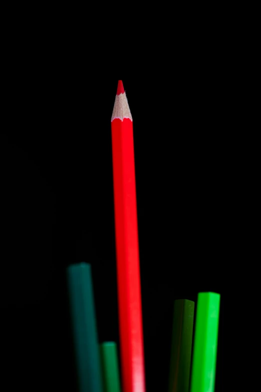 colored pencils in a glass container against a black background