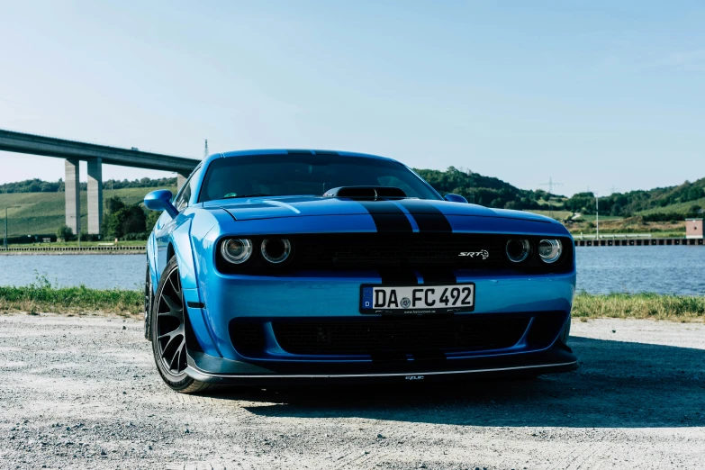 a blue car parked near a highway and a bridge