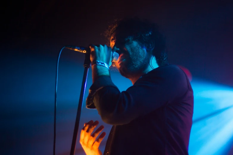 a man is singing into a microphone while the light is coming from behind him