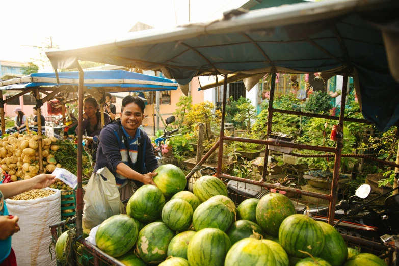 a group of people standing around lots of watermelons