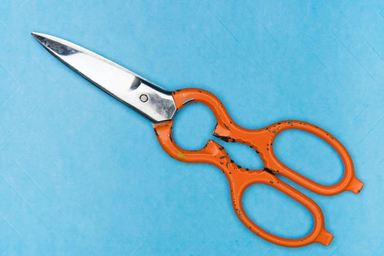 a red pair of scissors on a blue surface