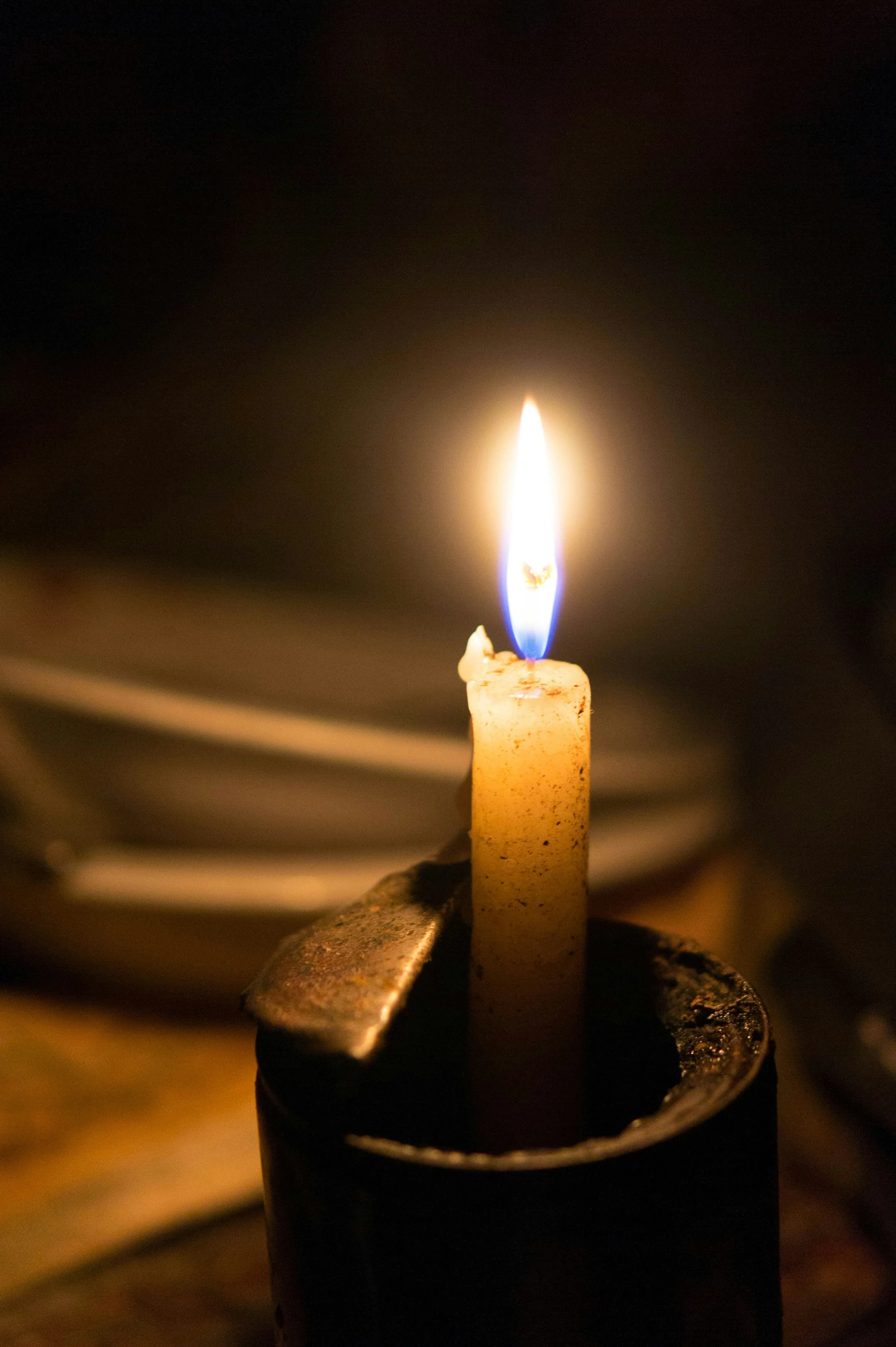 a single lit candle glowing in the dark