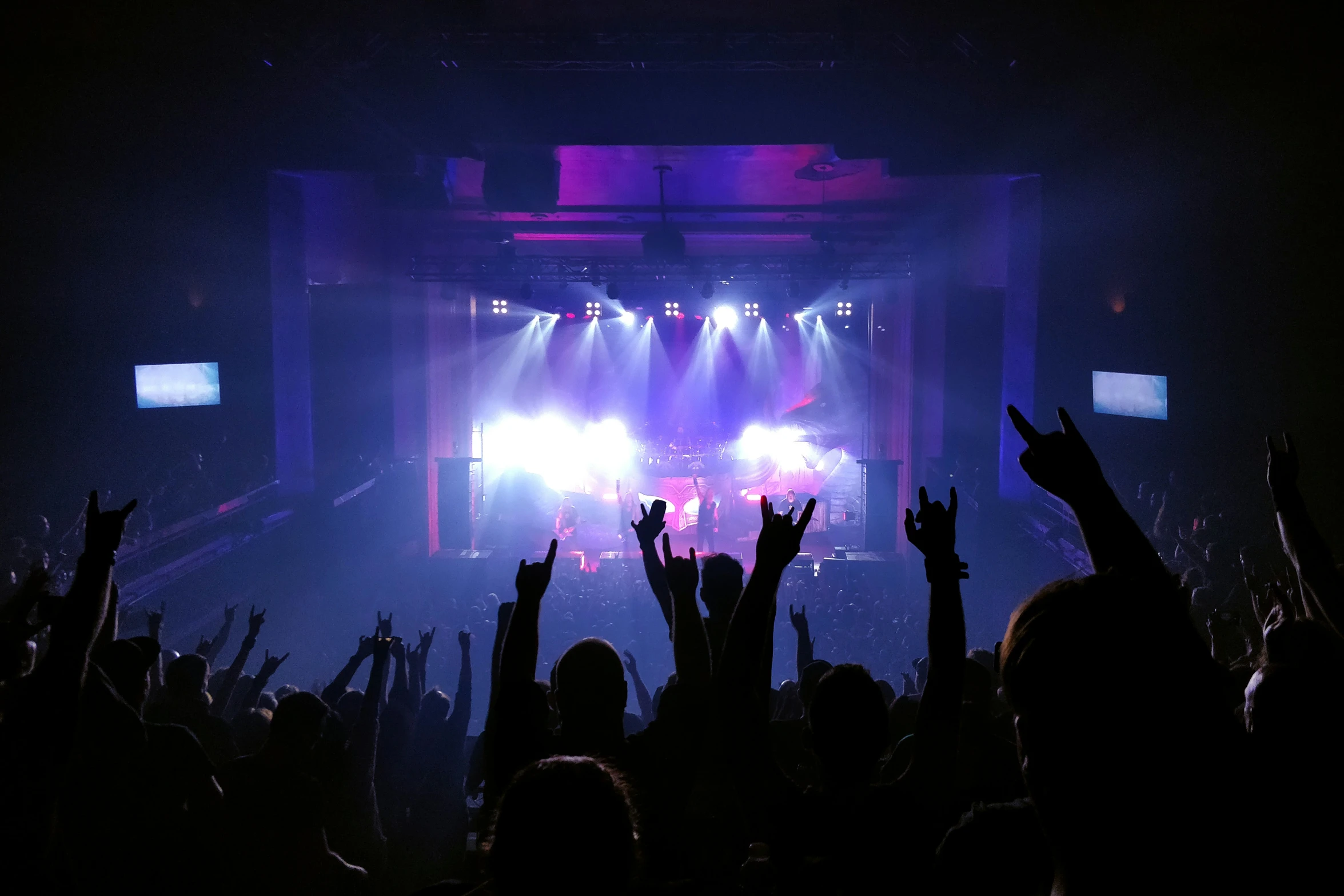 people in front of a stage with their arms up and hands in the air