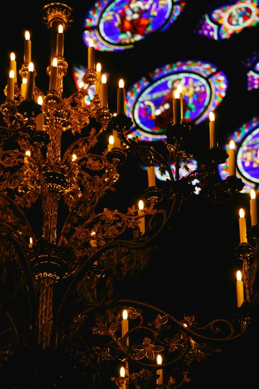 many lit candles in front of a cathedral window