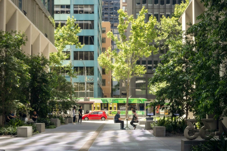 people are standing on a city walkway under trees