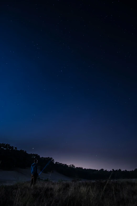 a man with his back pack looking up at the stars in the night sky