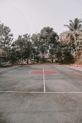 an empty basketball court sitting in a park next to a fire hydrant