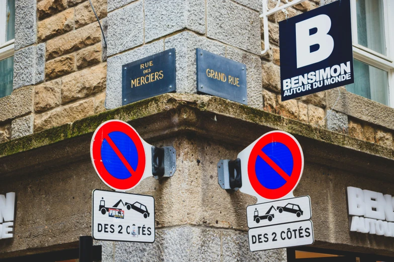 two red and blue traffic signs mounted to a stone building