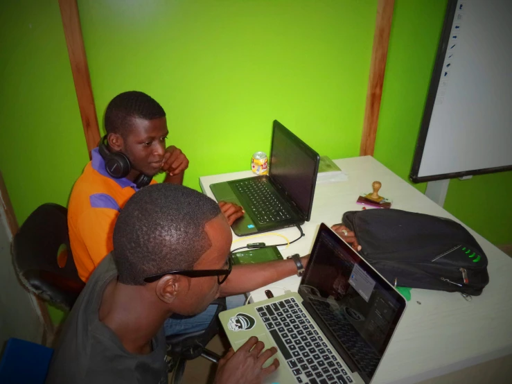 two boys are looking at computers on a table