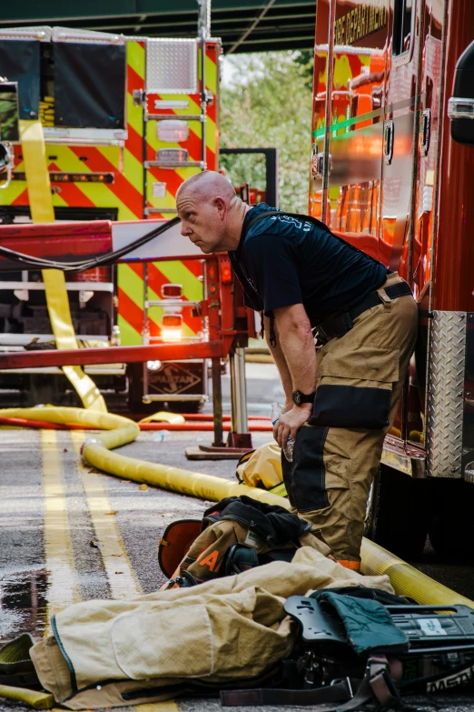 the man is fixing a fire hose near the yellow fire hydrant