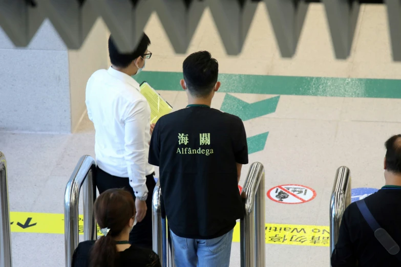 two men and one woman walking up and down an escalator