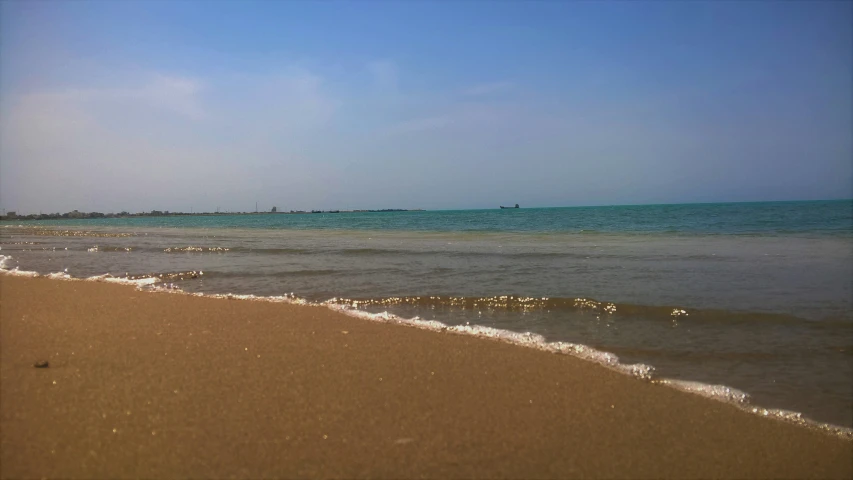 the sandy beach has waves coming in from the ocean