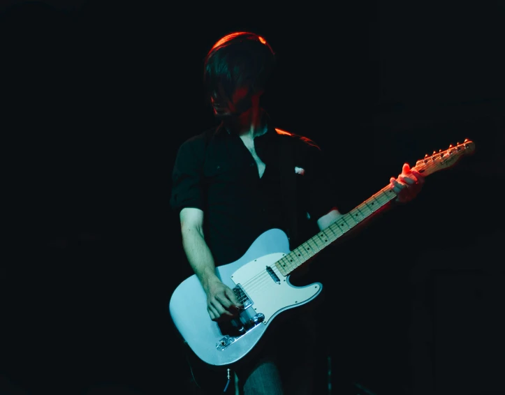 a woman holding onto her electric guitar in a dark area