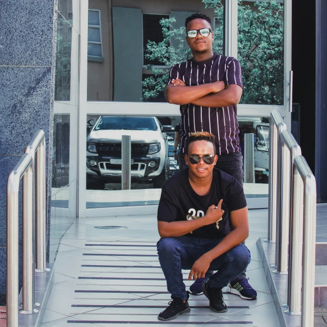 two young men posing for a po while sitting on some stairs