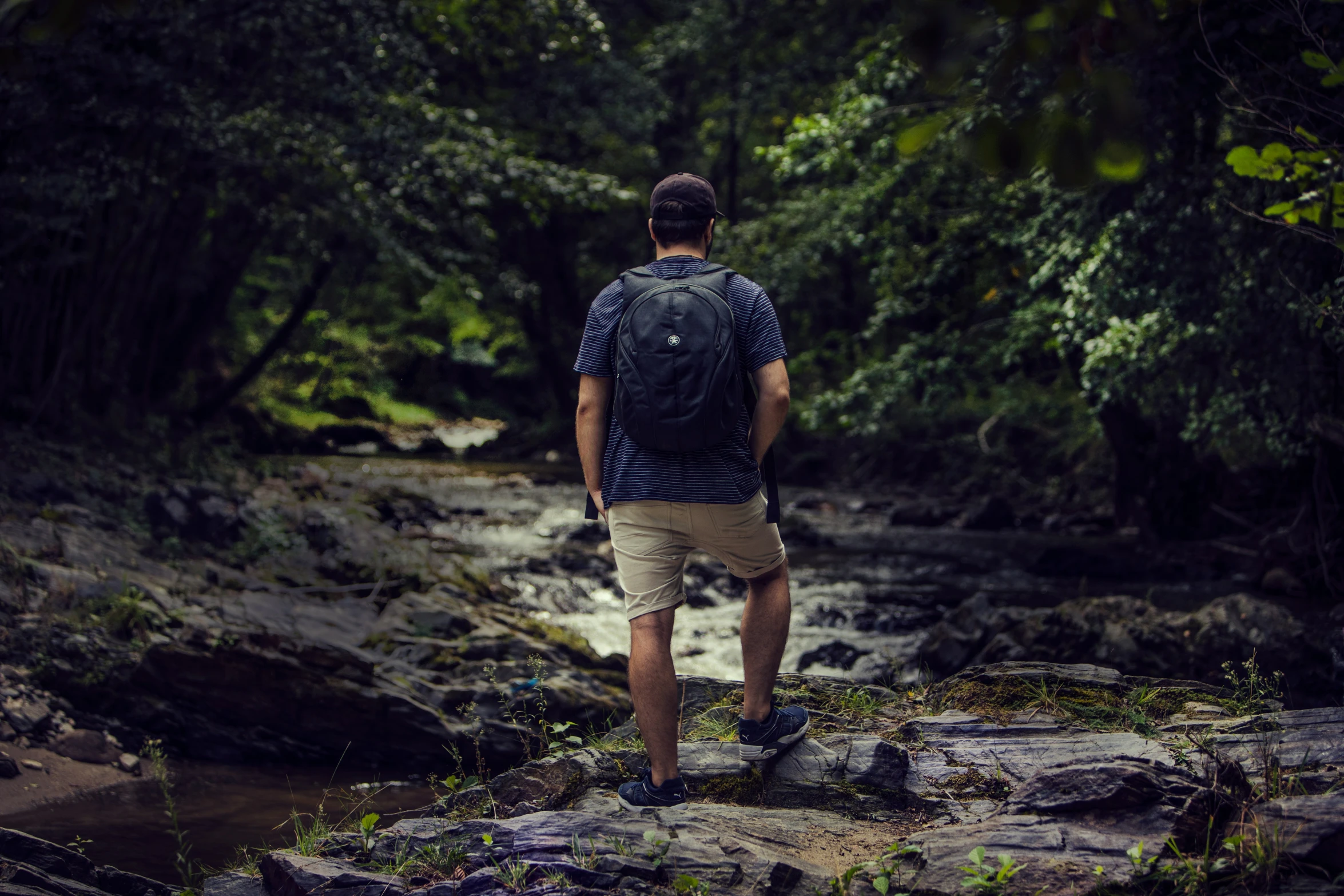 man in blue and white shirt walking on edge of water