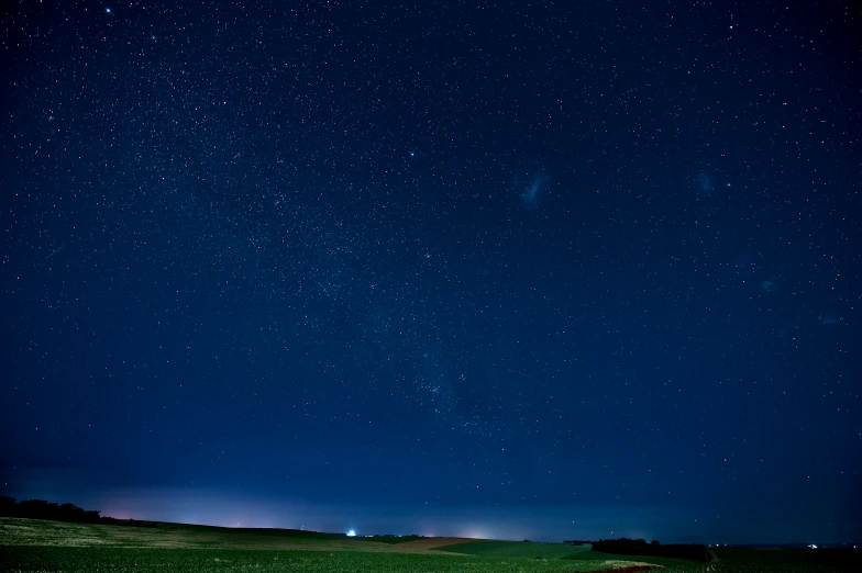 a grassy field with a night sky full of stars