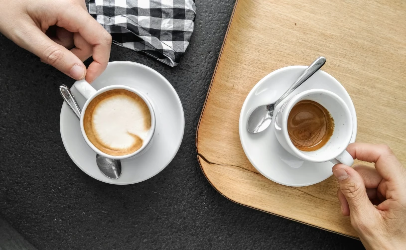 two people are holding coffee cups while they have a spoon in their hand