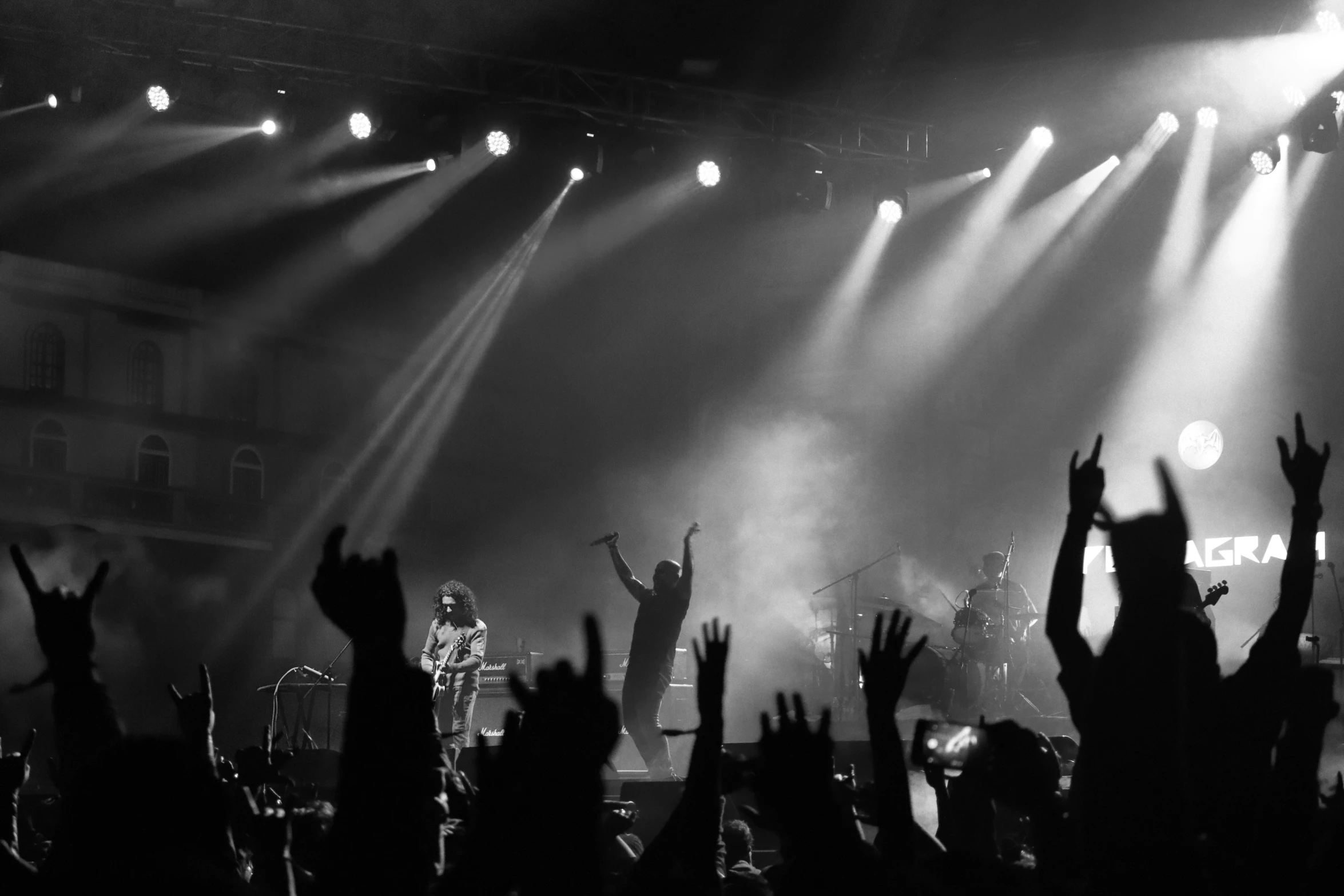 several people are silhouetted by the lights of a concert