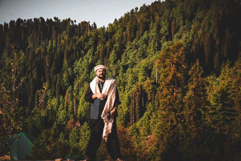 an indian man stands in front of some trees