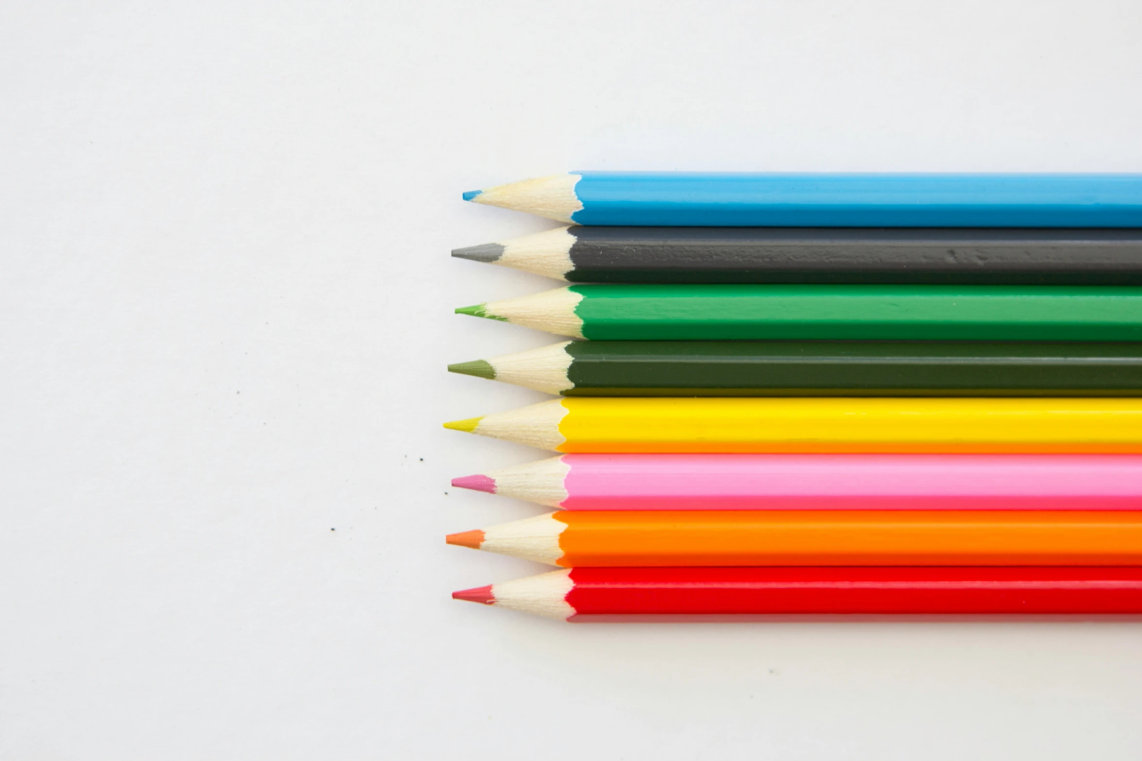 colored pencils on a white surface lined up