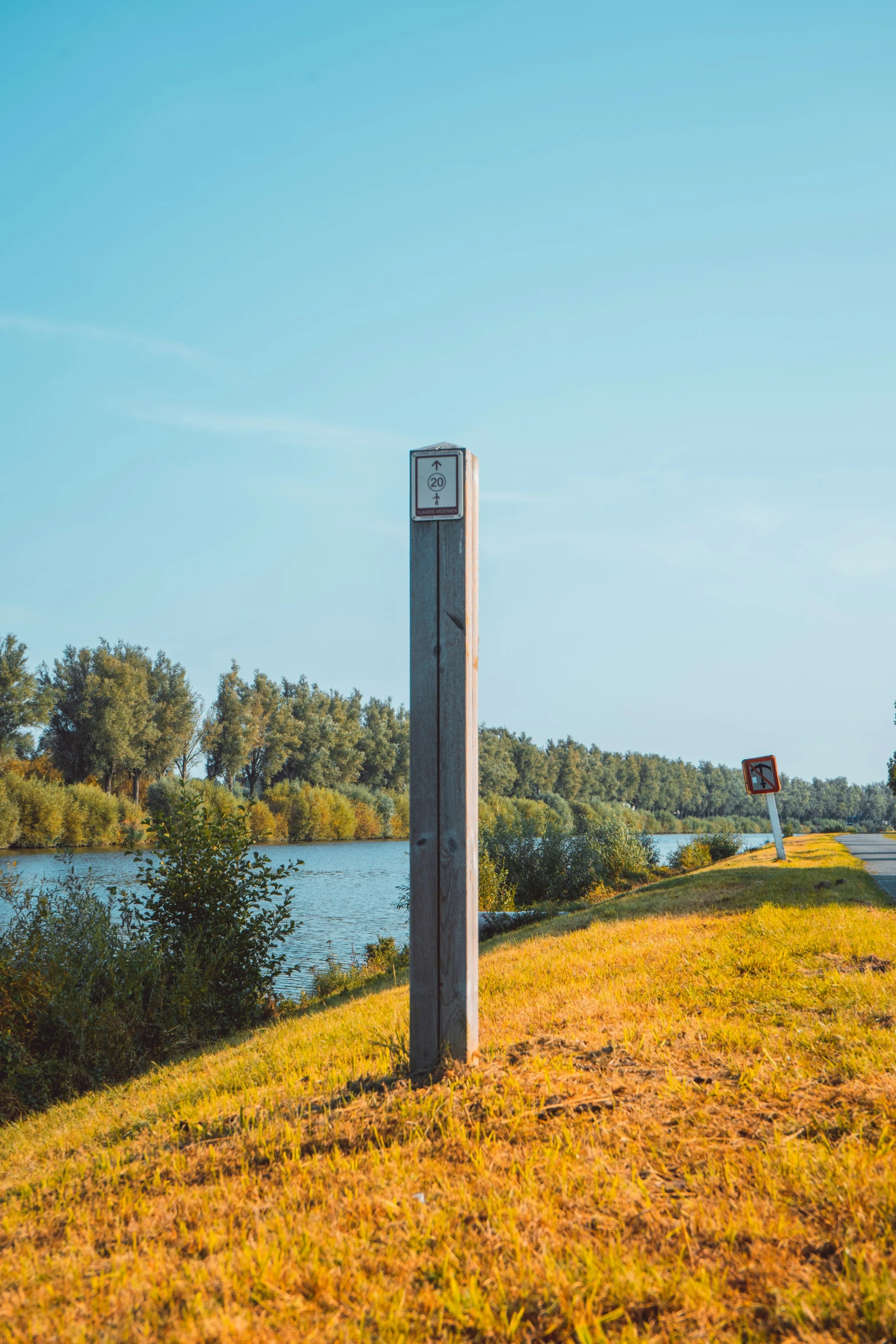 a street sign standing on a patch of grass next to a river