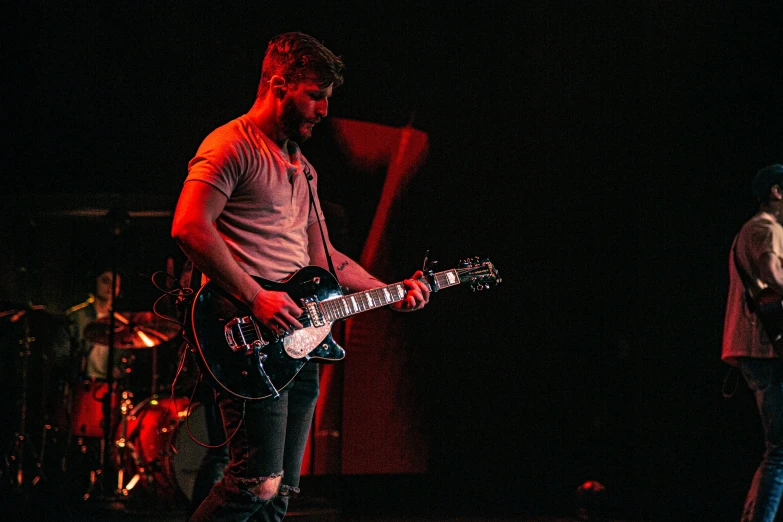 the man is playing his electric guitar on stage