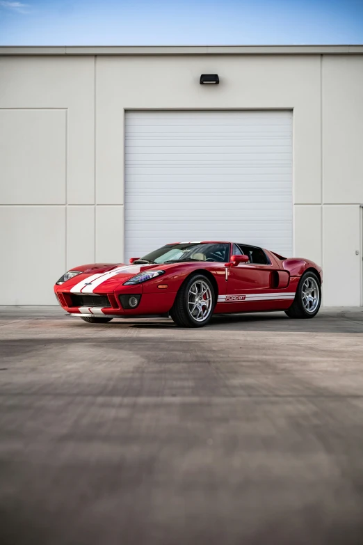 a red sports car sits in front of a garage