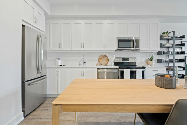 an empty kitchen with stainless steel appliances and wood table