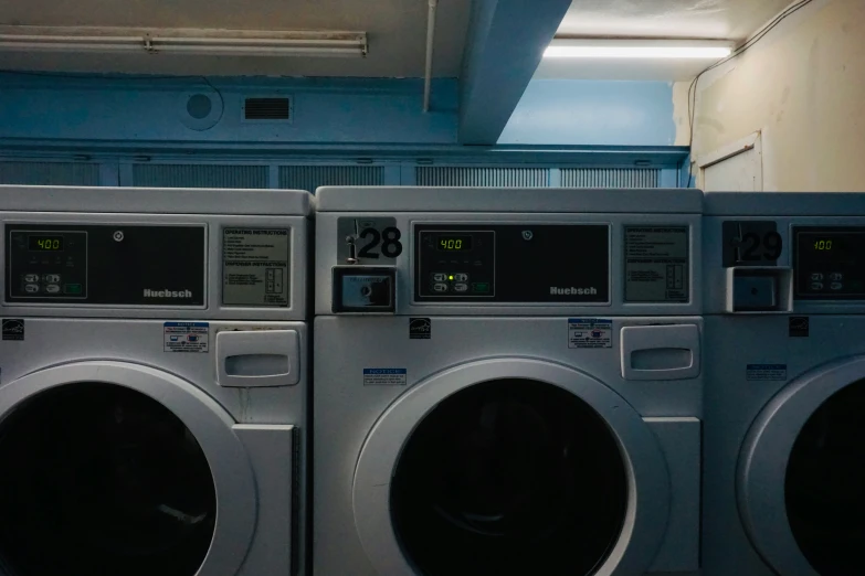 three industrial washing machines sitting side by side in a warehouse