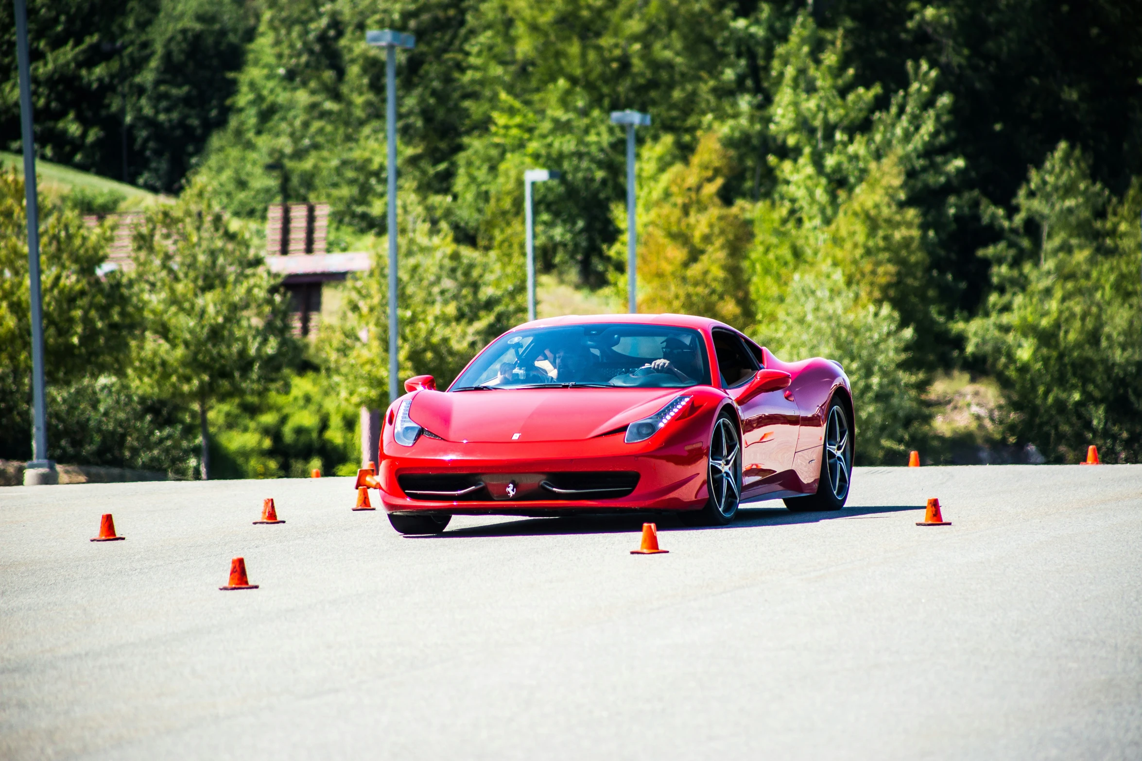 the red sports car is driving in front of cones