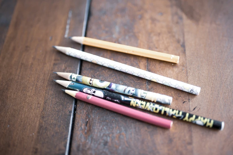 five pencils with halloween pictures are lined up on a wooden surface