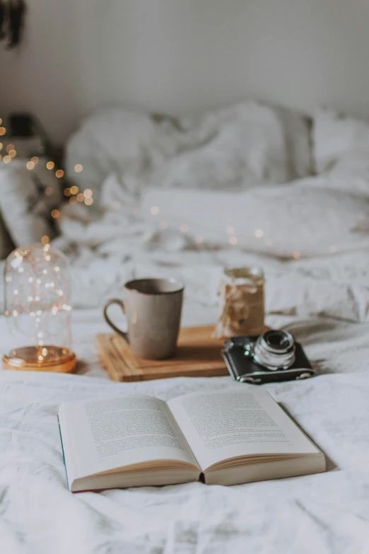 two books open on a bed, with coffee in the background