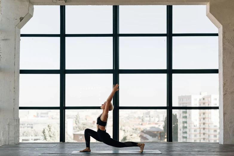 woman practicing yoga, doing the plank in front of a window