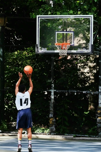 a young man in shorts playing basketball on an outdoor court