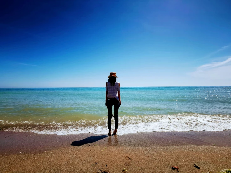 a person is on the beach, standing near the ocean water