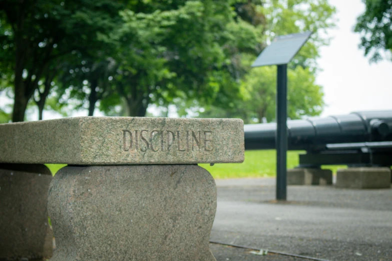 a granite bench in front of a sign on a post