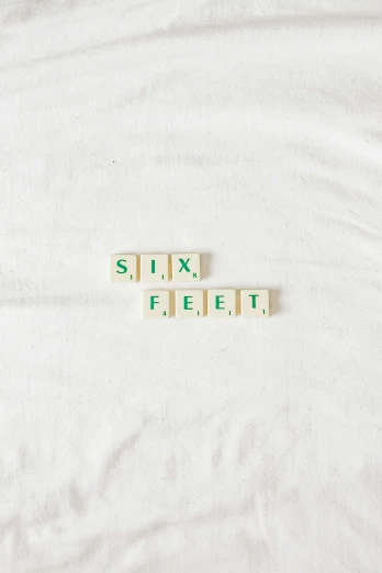 a sheet with two different scrabble letters that spell out six feet