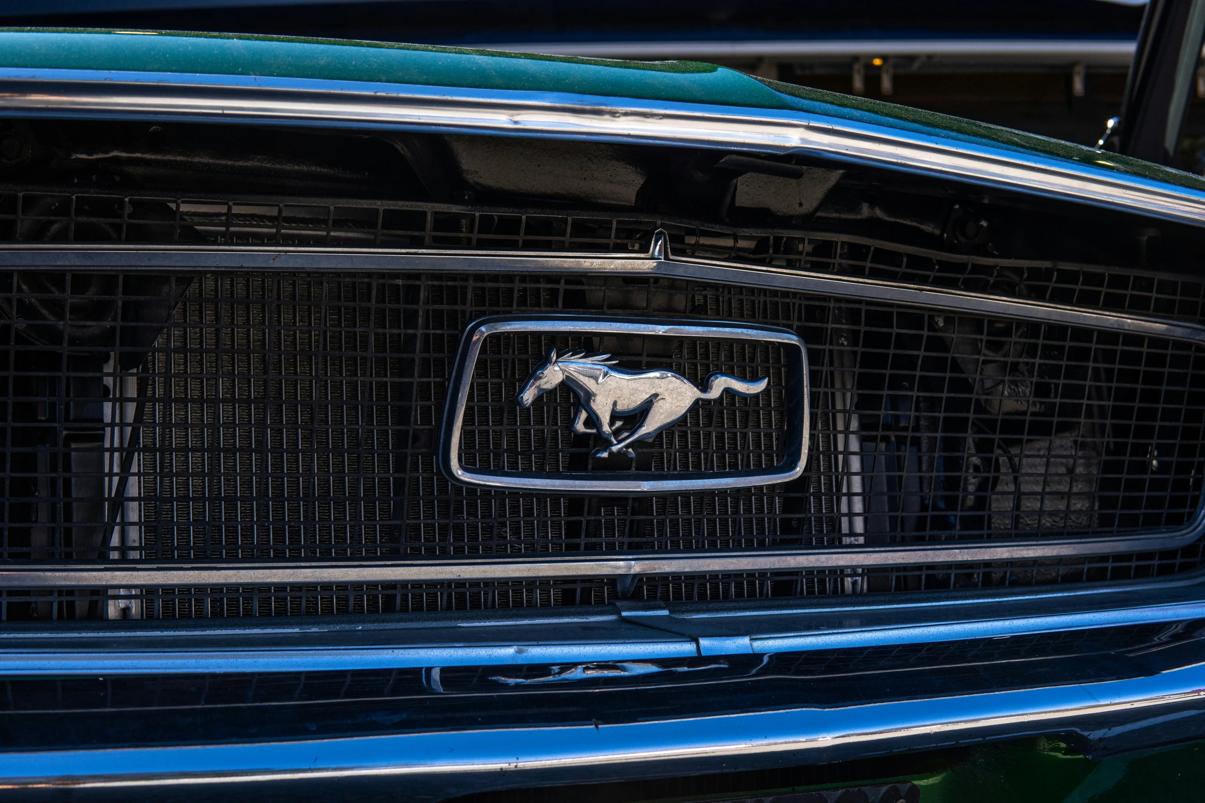a green car with a horse emblem on the grille