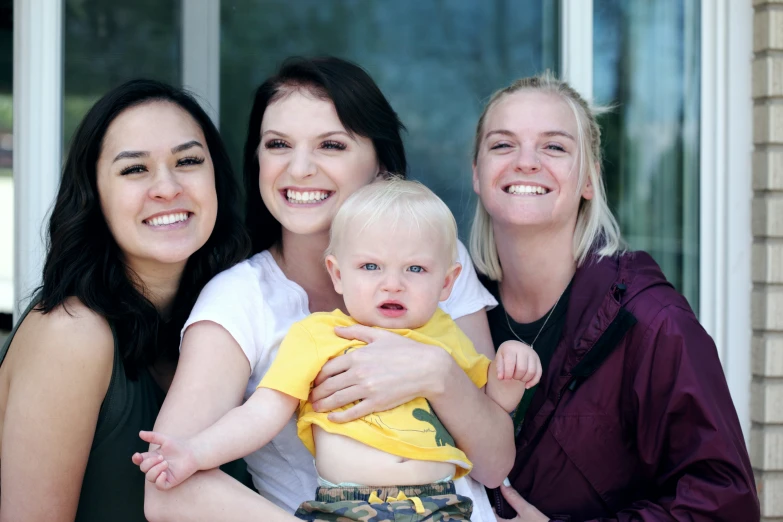 there are four women that are holding a baby
