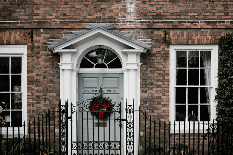 this house has white windows and a wreath with red berries in it