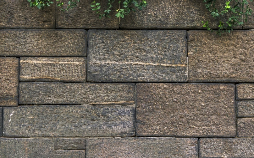 a stone wall covered with different sized and width blocks