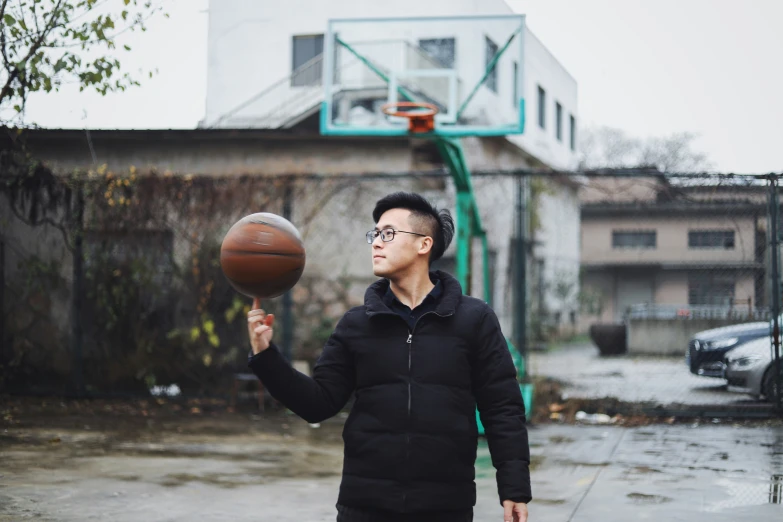 a man is holding a basketball on a wet street