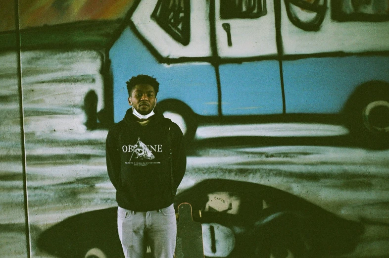 a man is posing with his skateboard in front of a bus painted wall