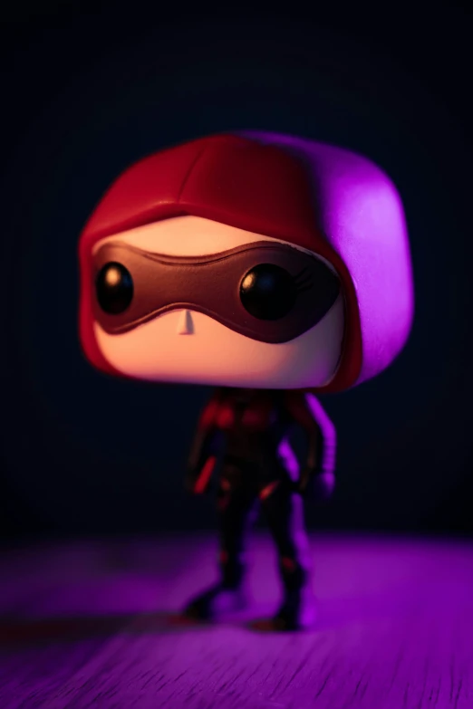 a little red mask hero figurine with purple lighting